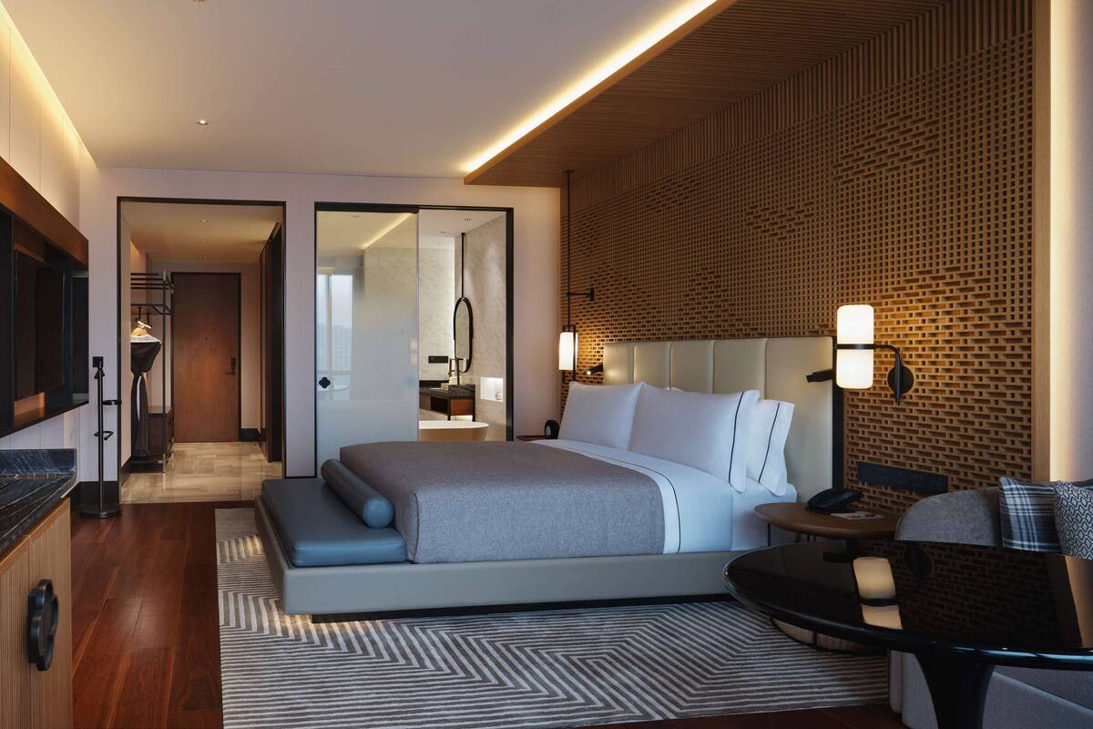 A modern hotel room with a large bed, a seating area with a table, and a television.