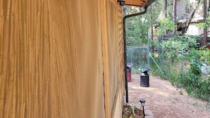 Un espacio al aire libre techado con techo de madera y vistas a un jardín con un sendero y plantas.
