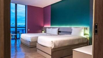 Quarto de hotel com duas camas, vista para a cidade e varanda.