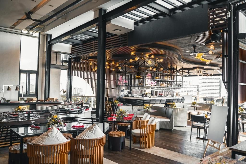 A modern restaurant with high ceilings, exposed beams, and a bar area.