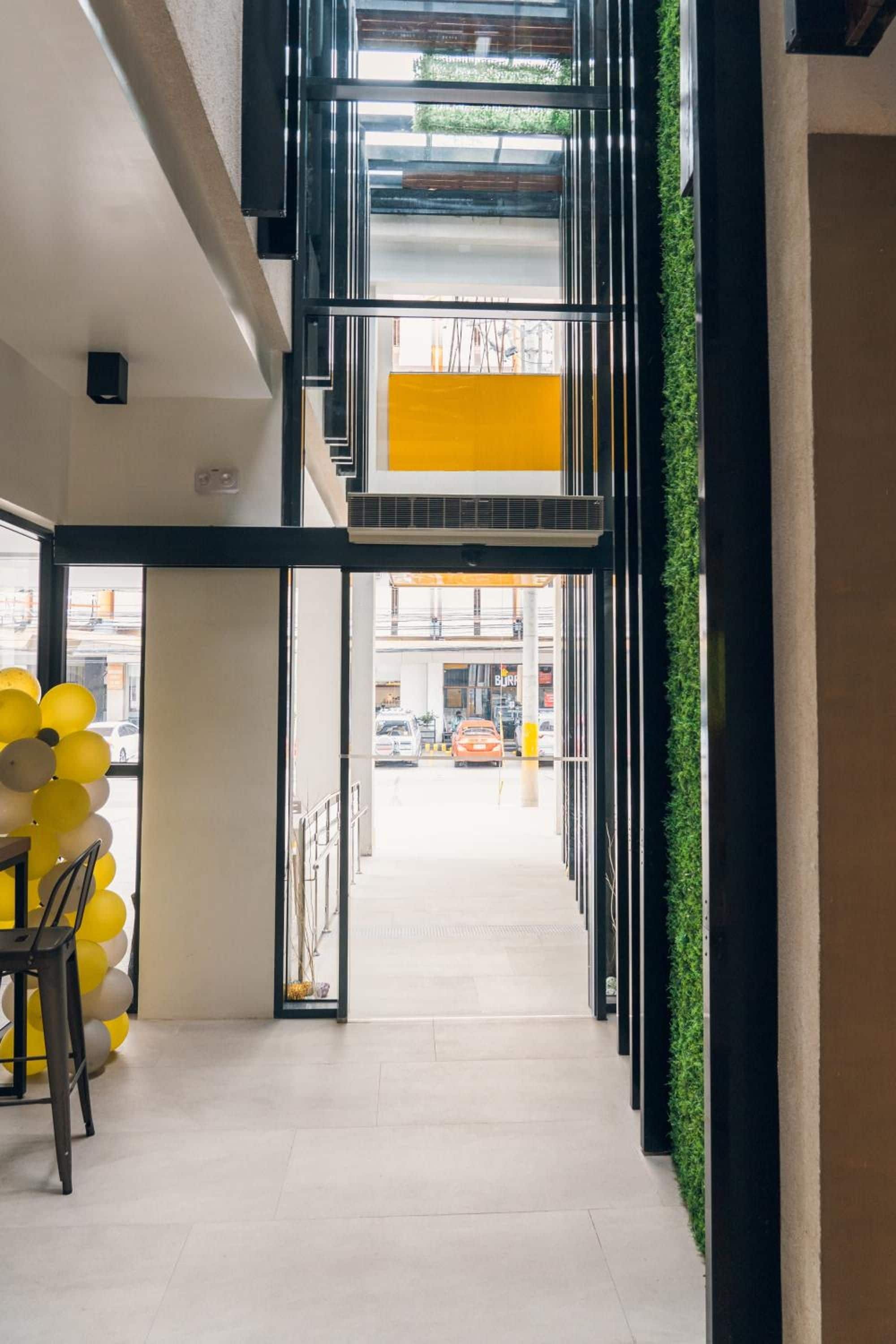 A modern interior with a staircase leading to an outdoor area, a yellow wall, and a view of the street.