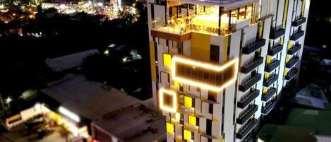 Un hotel de varios pisos con un diseño moderno, que cuenta con balcones y una terraza en la azotea.