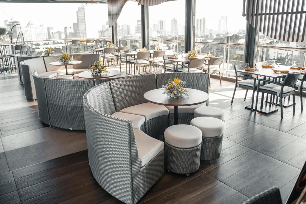 A rooftop dining area with round tables, wicker furniture, and city views.