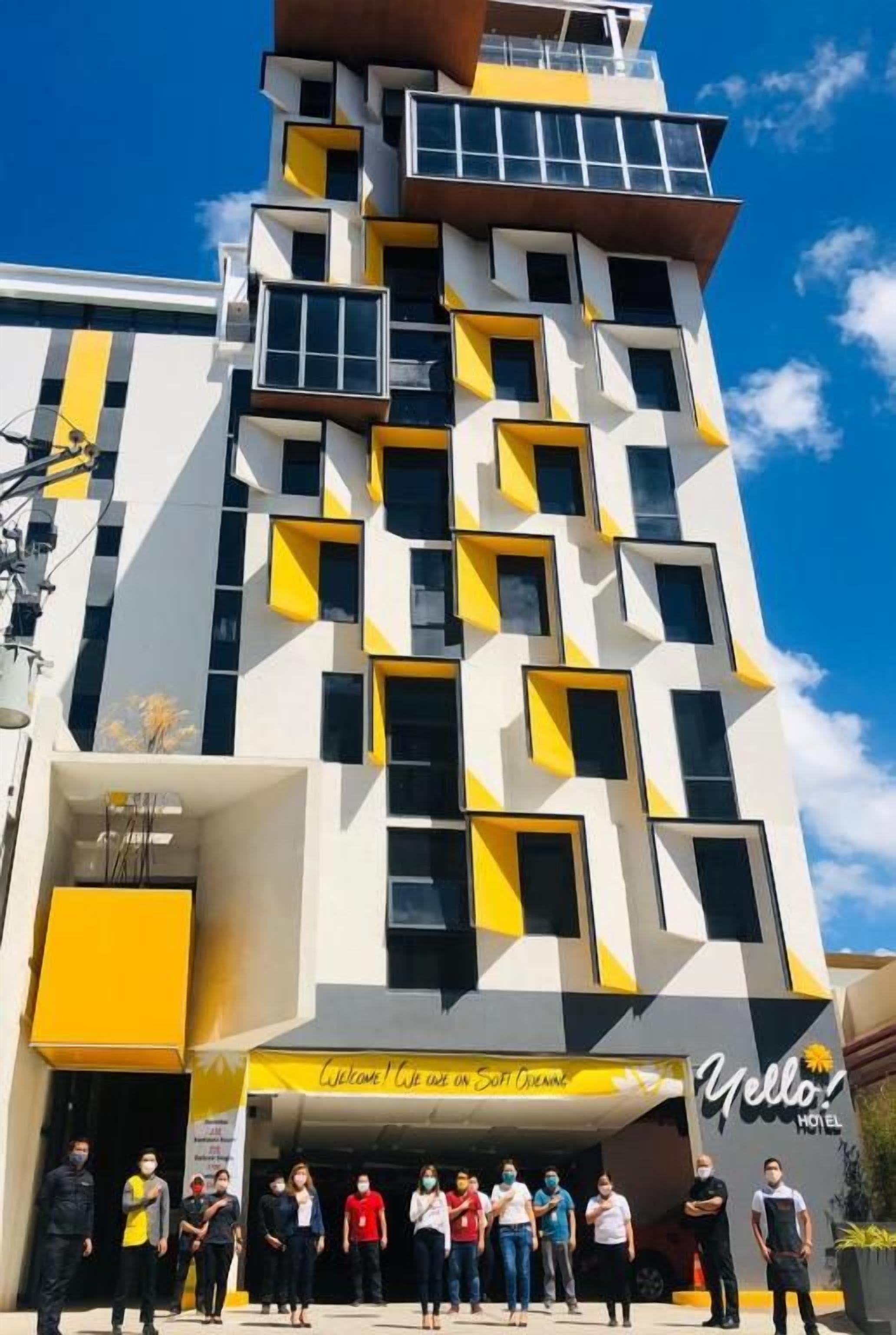 A modern hotel with a geometric facade, a welcoming entrance, and a visible signboard.