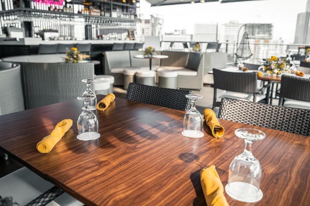 Un restaurant avec un bar à l’arrière-plan, des tables et des chaises, et une vue sur la ville.