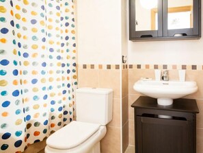 Een badkamer met toilet, wastafel en spiegel.