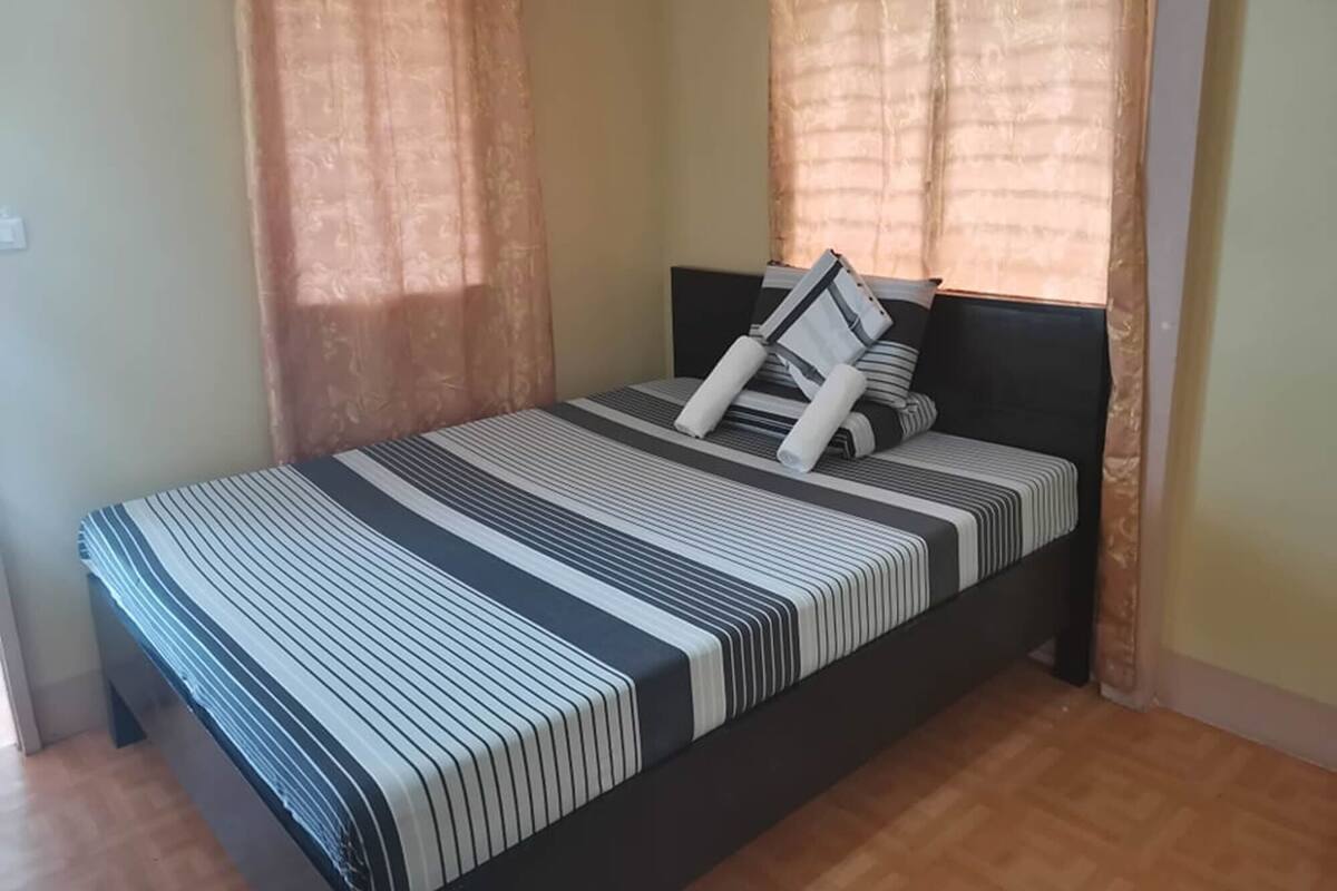 A single bed with a striped bedspread, two pillows, and a headboard.