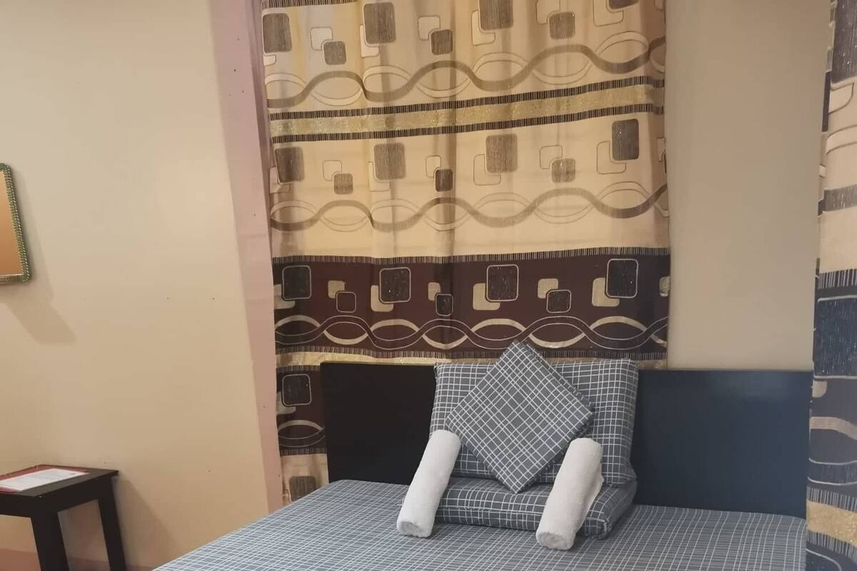 A neatly made bed with a blue and white checkered bedspread, two pillows, and a folded towel.