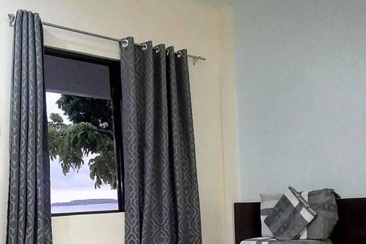 A bedroom with a bed, curtains, and a window with a view of trees.