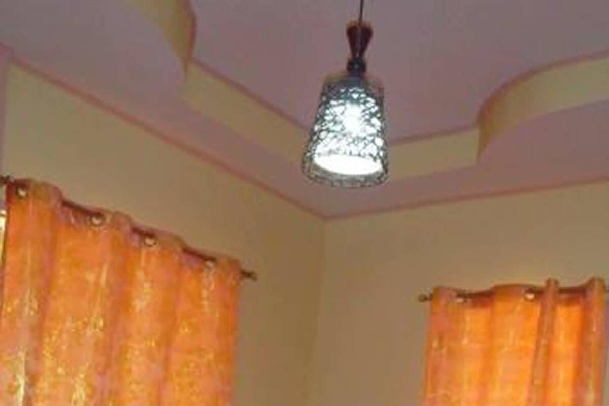 A bedroom with a bed, curtains, and a hanging light fixture.