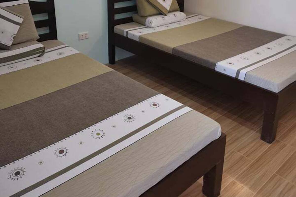 Two single beds with wooden frames and headboards, a small wall-mounted picture, and a wall clock.