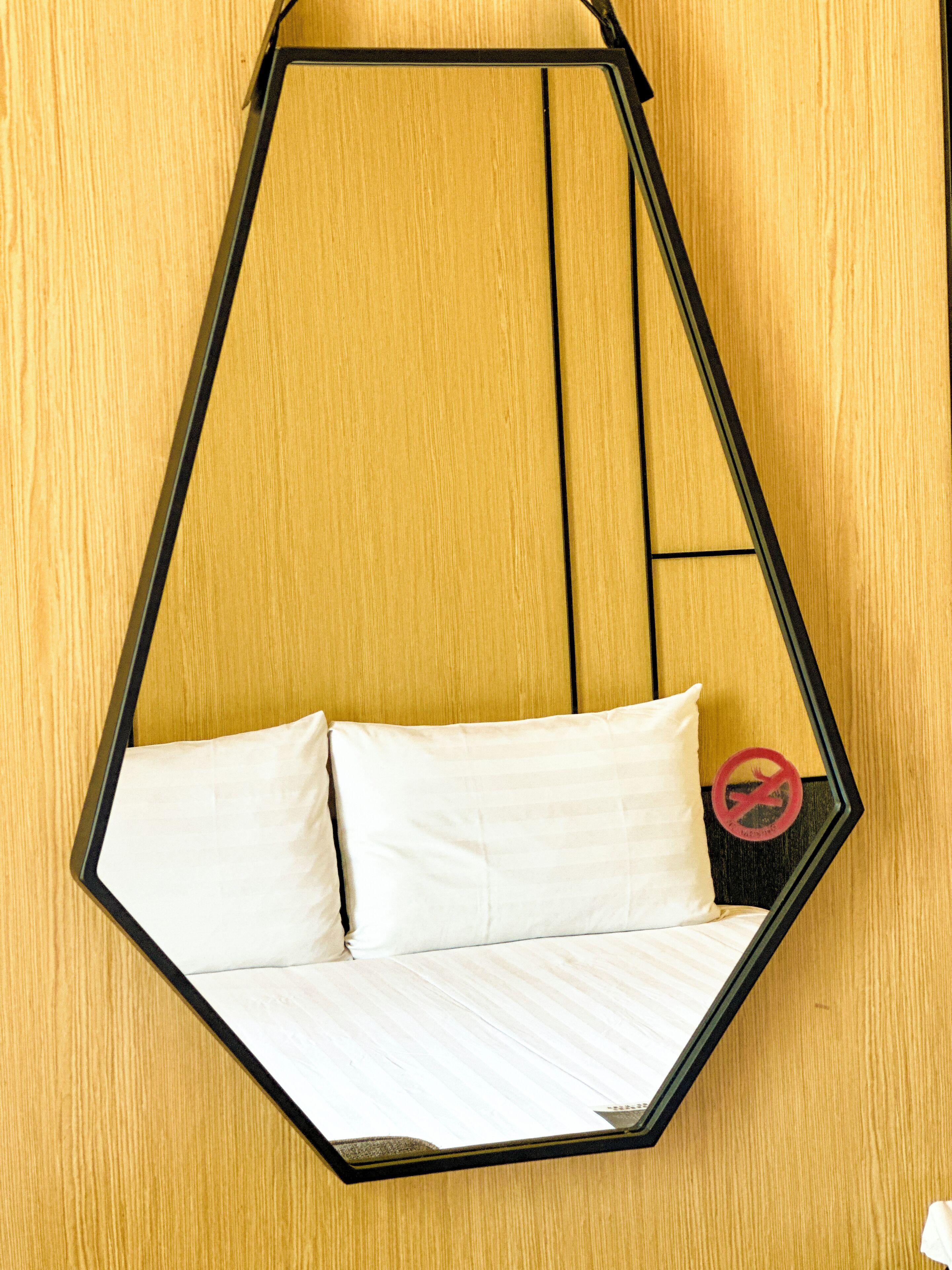 A hexagonal hanging bed with white bedding against a wooden wall.
