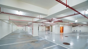 A spacious parking garage with clear markings for parking spaces, red pipes overhead, and a clean, well-lit environment. - Hotel A . Tainan (Tainan)