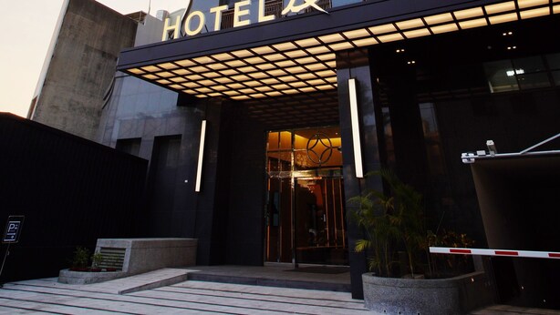 A tall hotel building with a modern design, featuring a prominent entrance with a glass canopy and a sign that reads "HOTEL". - Hotel A . Tainan (Tainan)