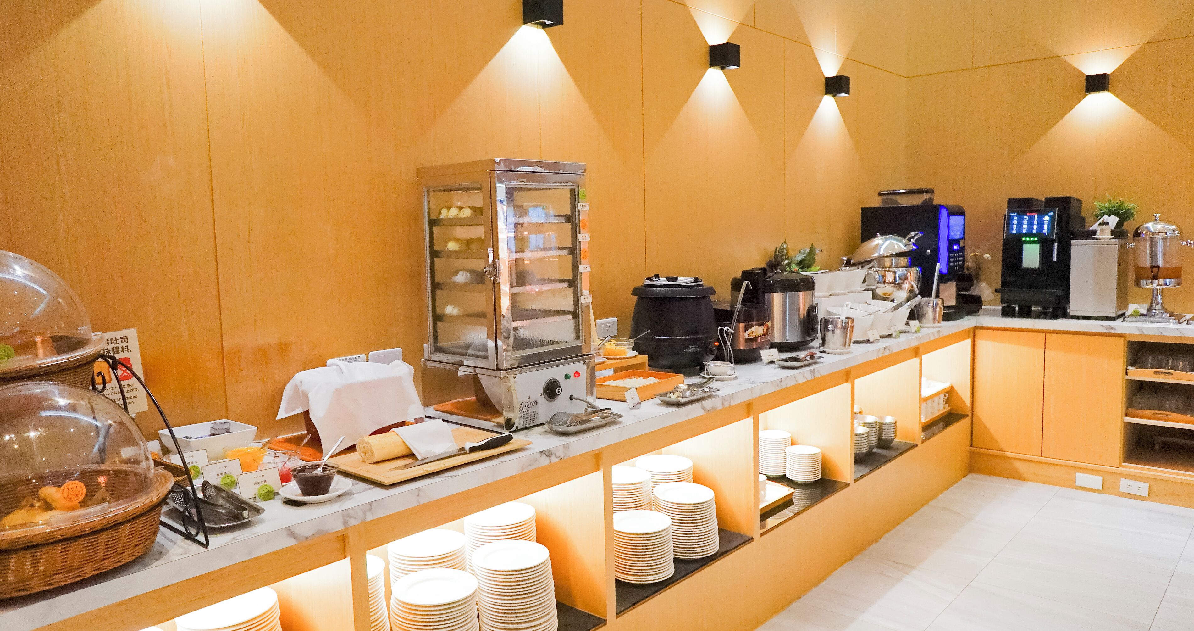 Montaje de bufé con diversos alimentos, una máquina de café y dispensador de bebidas.