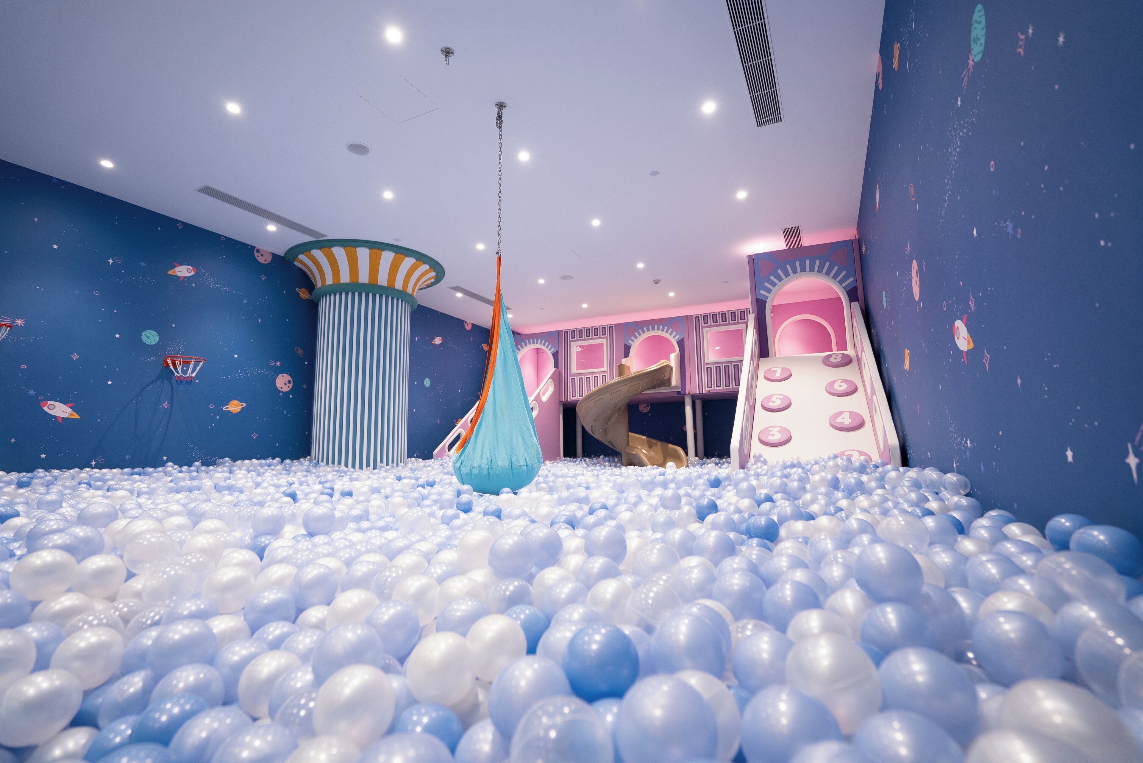 Un área de juegos con piscina de pelotas, columpio colgante y tobogán.