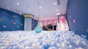Un área de juegos con piscina de pelotas, columpio colgante y tobogán.