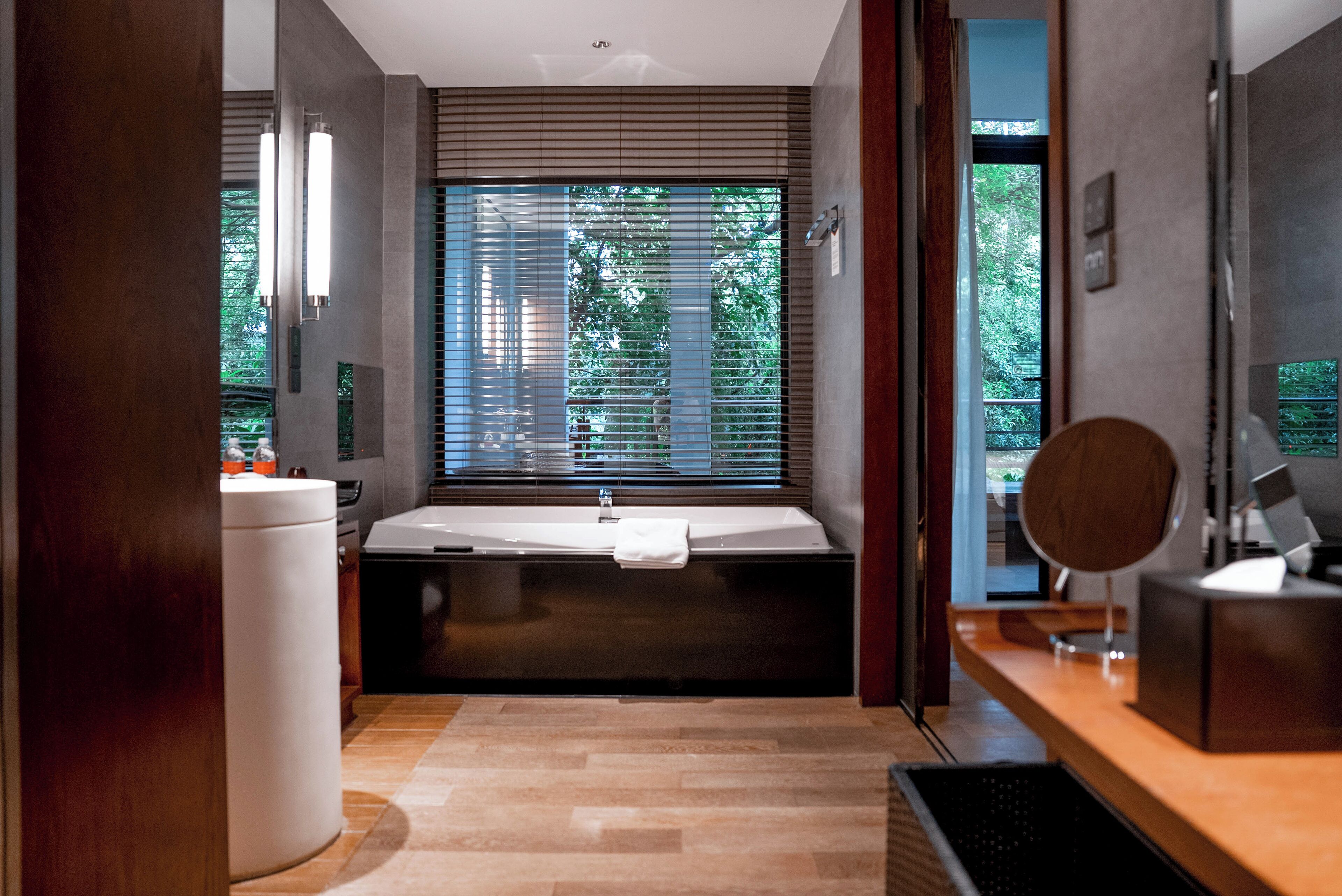 A modern bathroom with a large bathtub, a sink, and a mirror.