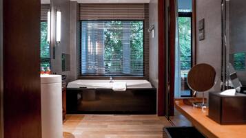 A modern bathroom with a large bathtub, a sink, and a mirror.