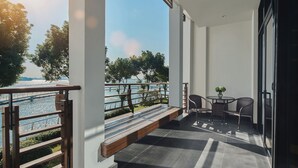 Un balcon donnant sur une rivière, une table avec des chaises et une rambarde.
