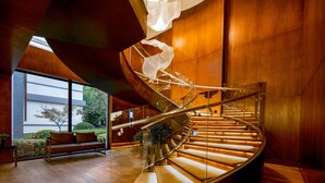 Un intérieur moderne avec un escalier à volutes, un plancher en bois et une balustrade en verre.