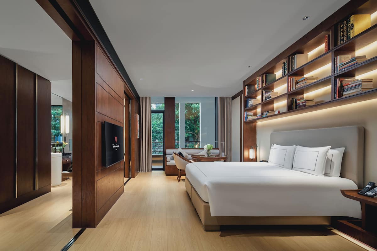 Une chambre d’hôtel moderne dotée d’un grand lit, d’une télévision, d’une bibliothèque et offrant une vue sur l’extérieur.