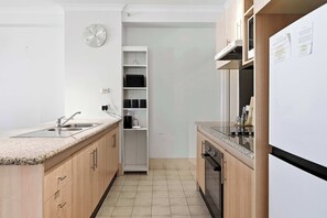 A modern kitchen with a built-in oven, a sink, and a white refrigerator.