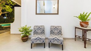 A room with two patterned chairs, a mirror, a potted plant, and a small table. - Akaya Bali (Denpasar)