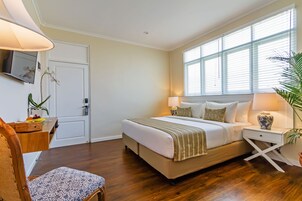 A bedroom with a bed, bedside tables, a TV, and a window with blinds.
