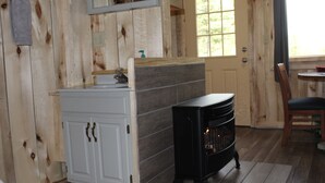 A room with a white cabinet, a black stove, and a wooden door. - Sweet Seclusion Cabin with Shower (Healy)