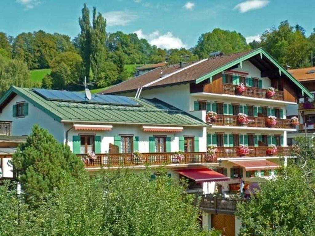 Un immeuble à plusieurs étages doté de balcons, d’un toit végétalisé et d’une antenne parabolique bien visible.