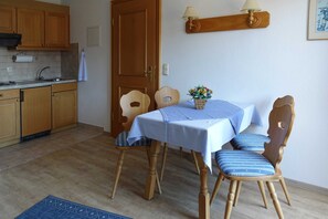 A dining area with a table set for two, wooden chairs, a small table lamp, and a wall-mounted shelf with a lamp. - Paraplui - House Schußmann (Tegernsee)