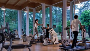 Une salle de sport équipée de nombreux appareils de cardio, dotée de grandes fenêtres et d’un plancher en bois.