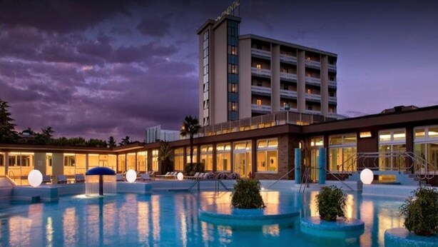 Un hôtel doté d’une piscine, un immeuble imposant avec de nombreux balcons et une entrée bien éclairée.