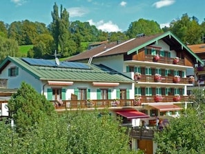 Ein mehrstöckiges Gebäude mit Balkonen, einem begrünten Dach und einer sichtbaren Satellitenschüssel.