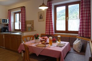 A cozy dining area with a table set for two, a sofa, and a window with curtains. - Neureuth - House Schußmann (Tegernsee)