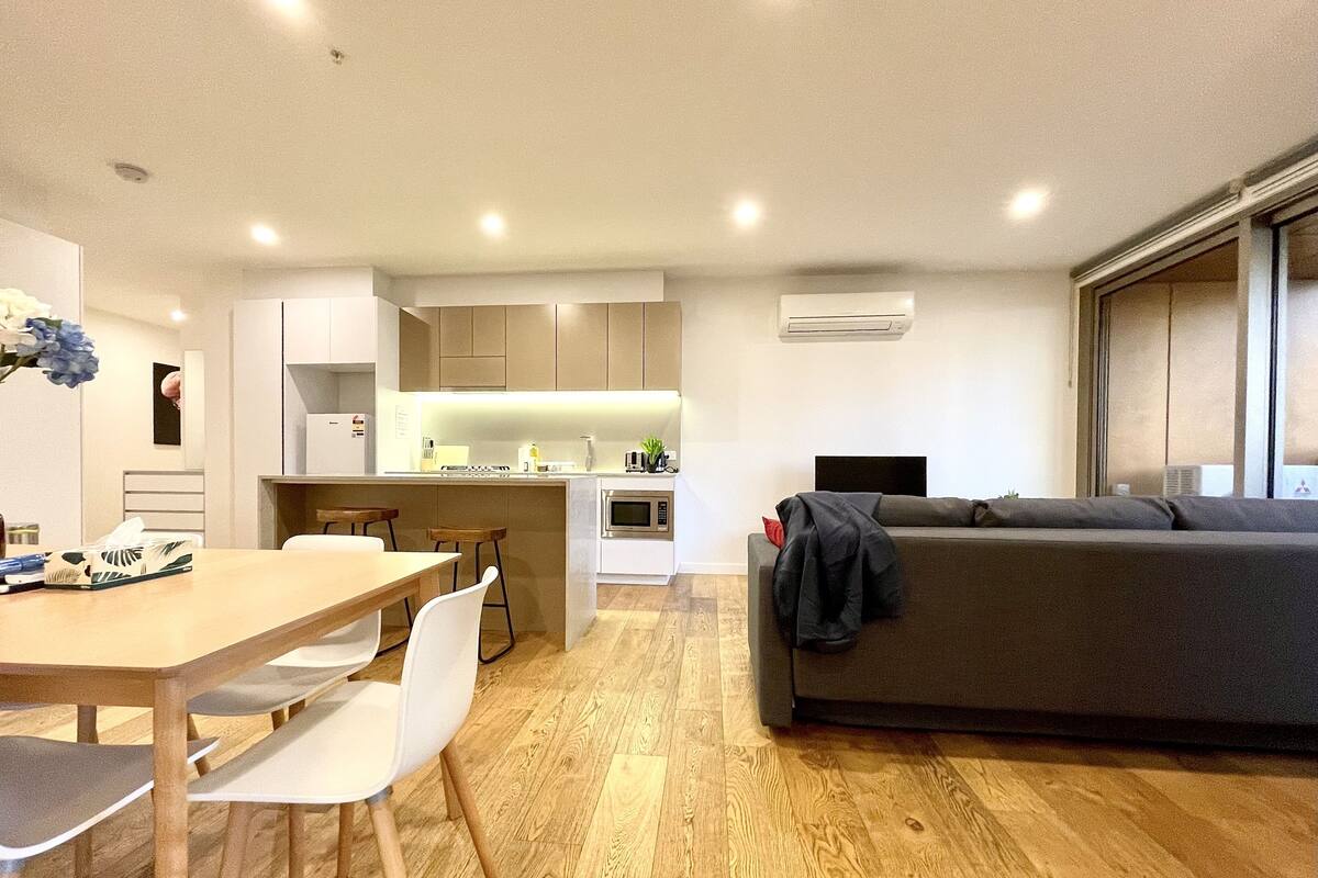 A modern living space with a dining area, kitchen, and a sofa.
