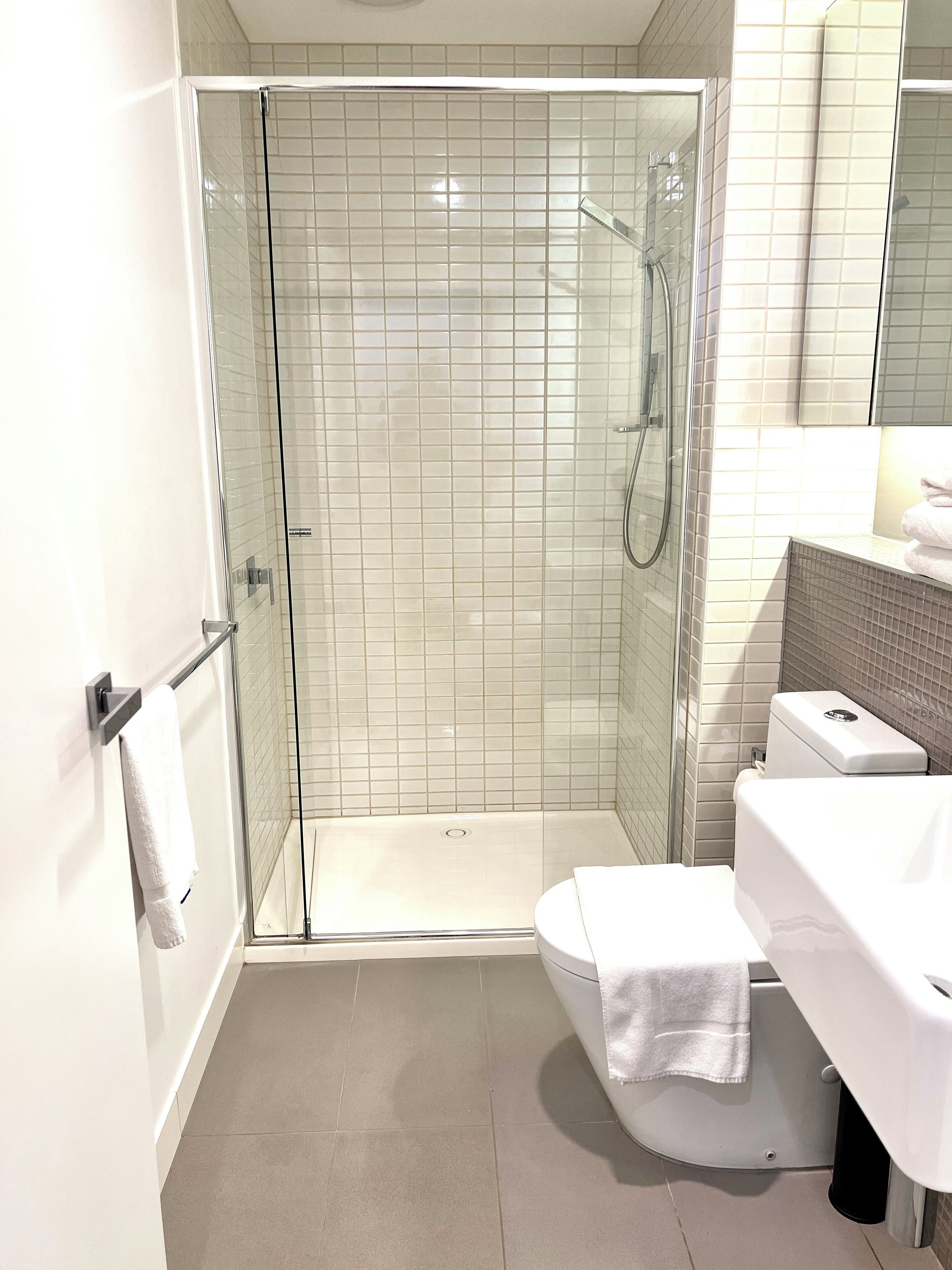 A modern bathroom with a glass-enclosed shower, a white toilet, and a sink with a towel on it.