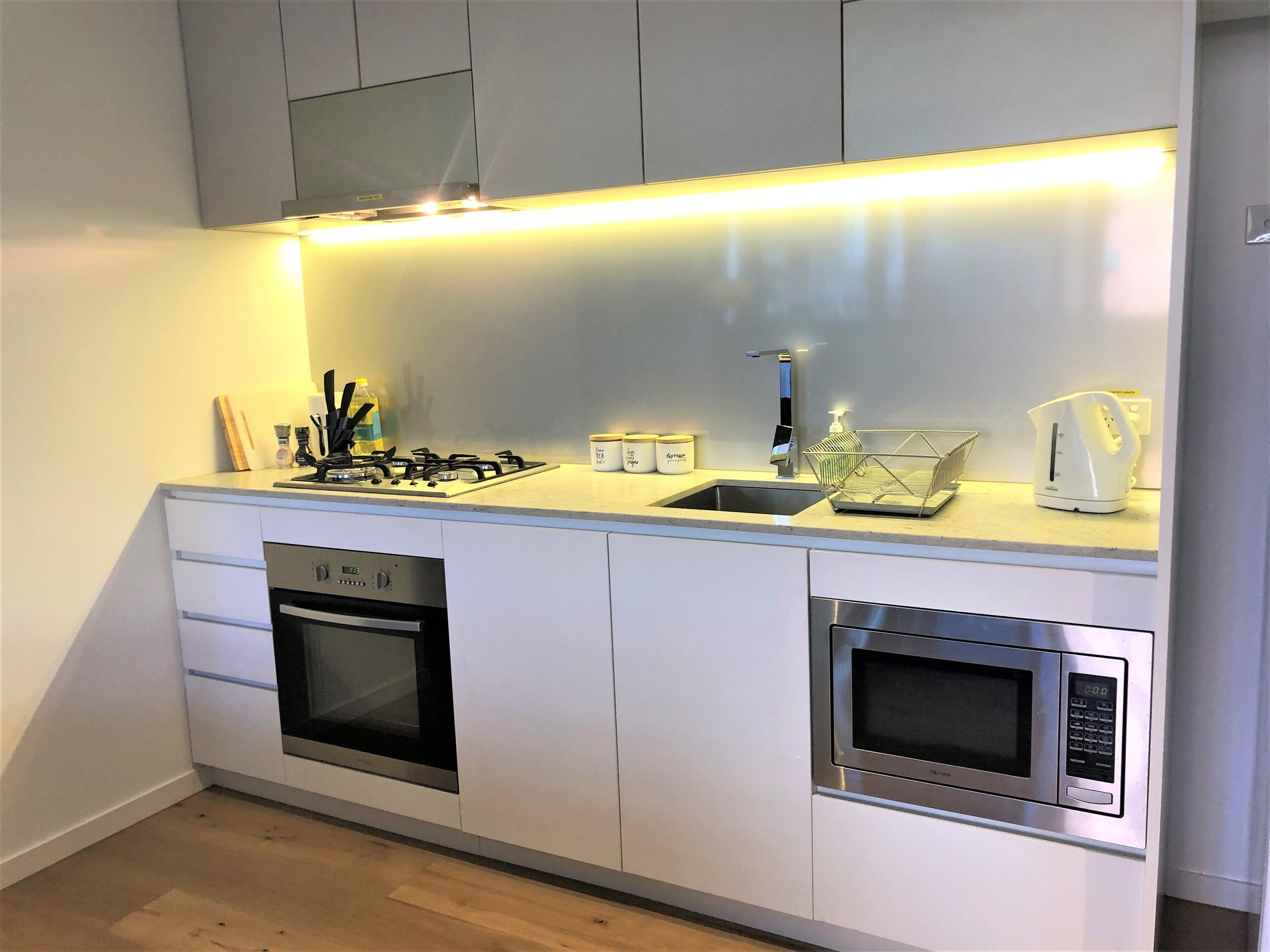 A modern kitchen with a gas stove, built-in oven, microwave, and a stainless steel sink.