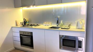 A modern kitchen with a gas stove, built-in oven, microwave, and a stainless steel sink.