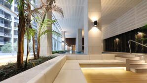 Un espace intérieur moderne doté d’un escalier central, de coins salon et d’un élément décoratif aquatique.