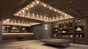 A modern bar area with a reception desk, a seating area with a bench, and a brick wall with shelves displaying various items.