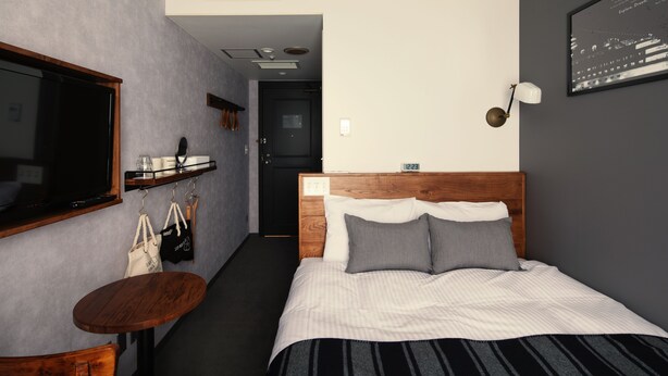 A hotel room with a bed, a TV, a small table, and a mirror.