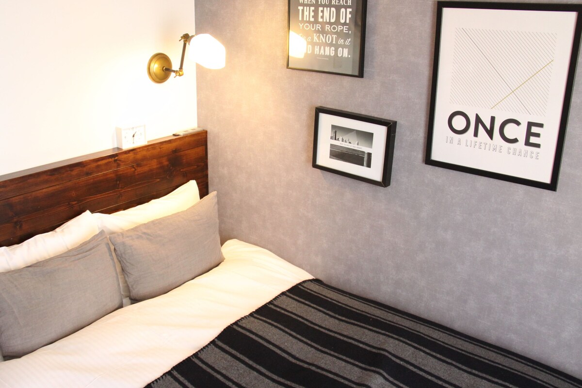 A neatly made bed with a wooden headboard, a bedside lamp, and a framed motivational quote on the wall.