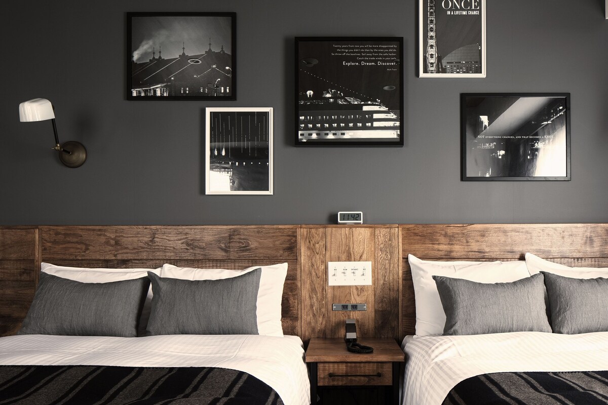 Una habitación de hotel con una cama grande, dos mesitas de noche y un reloj de pared.