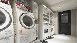 A laundry facility with multiple washing machines and a vending machine.