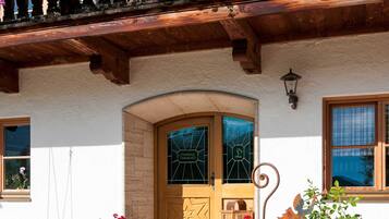 Ein traditionelles Chalet mit einem hölzernen Balkon, der mit bunten Blumen geschmückt ist, einer einladenden Holztür und einem kleinen Garten.