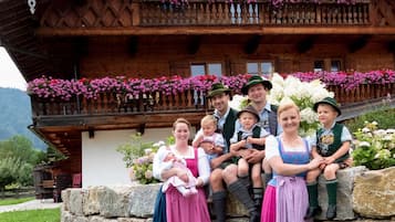 Ein Holzgebäude mit einem Balkon, der mit Blumen geschmückt ist, eine Steinmauer und eine Rasenfläche davor.