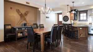 Una cocina amplia con una isla de madera, piso oscuro y una lámpara moderna.