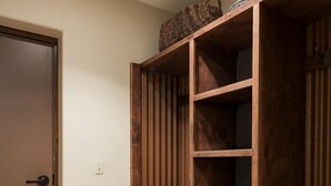 Un mueble de madera con estantes y un banco, una puerta y un interruptor de luz en la pared.
